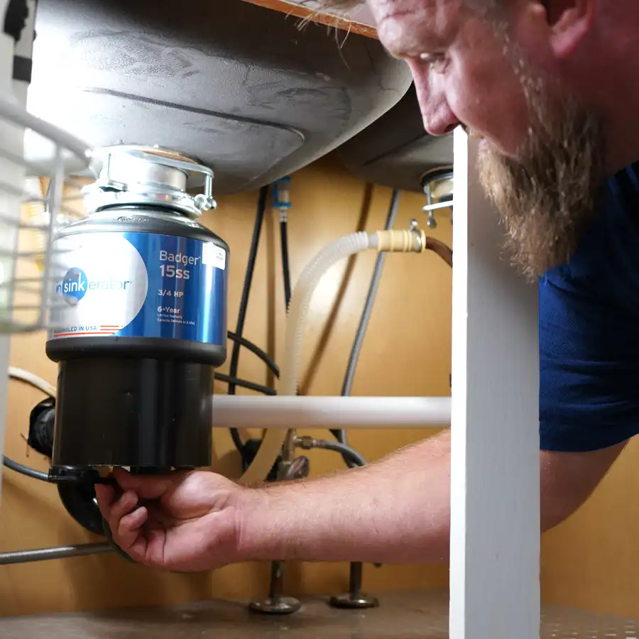 Plumber under a sink fixing a garbage disposal