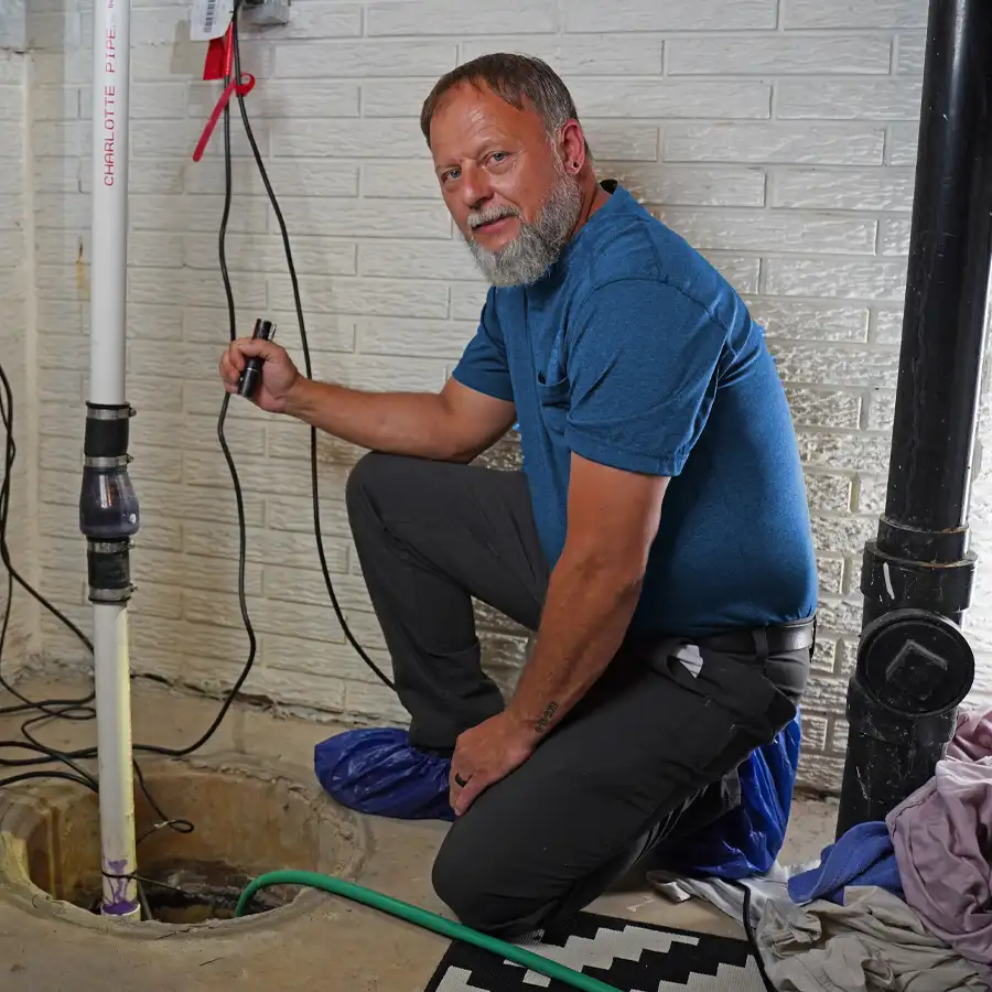 Plumber holding a flash light inspecting a sump pump