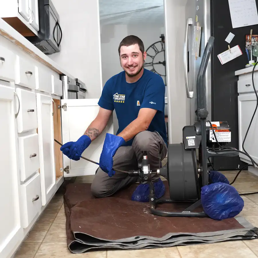 Plumber with plumbing equipment kneeling under a sink